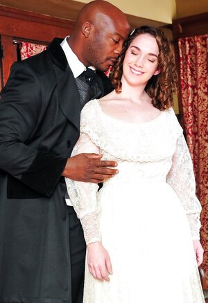 Pale-skinned broad in old-fashioned white dress kisses black dude in a suit