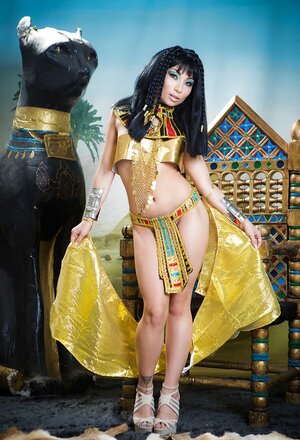 Far eastern babe plays the role of Cleopatra posing on a golden throne