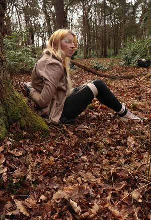 Broad with glasses can't stand up cuz she is hogtied by the tree