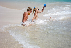 Group of youthful lascivious broads pose wholly undressed on the beach with no shame