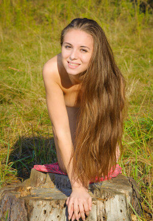 Winsome immature lady with long hair enjoys modeling undressed in the open air
